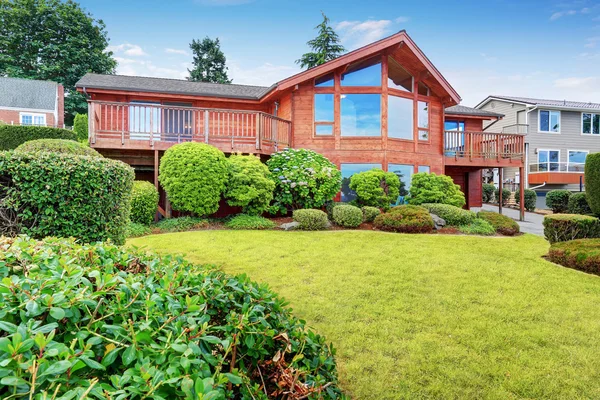 Casa de luxo exterior com guarnição de painel de madeira, garagem e jardim bem guardado ao redor . — Fotografia de Stock