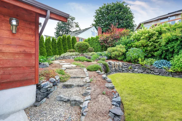 Jardín bien cuidado cerca de la casa con adornos de madera. Bonito diseño de paisaje . — Foto de Stock