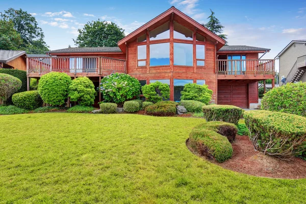 Luxe huis exterieur met houten paneel trim, garage en goed onderhouden tuin rond. — Stockfoto