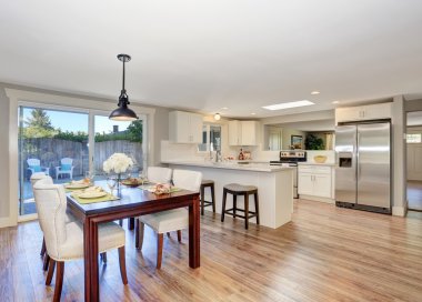 Zarif masa ayarı ve beyaz yumuşak sandalyeler ile açık kat planı yemek alanı.