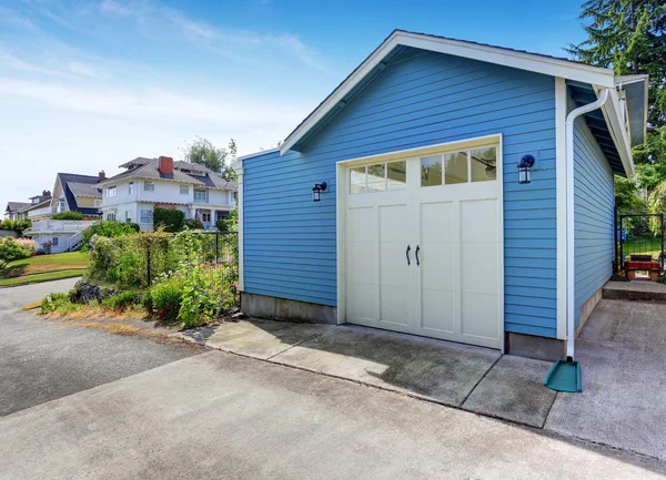 Fenced backyard with grass filled garden and small blue shed — Stock Photo, Image