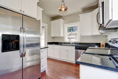 White kitchen room interior with granite counter top and hardwood floor.