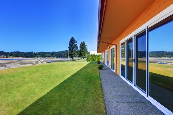 Patio trasero con césped bien cuidado y vista al agua — Foto de Stock