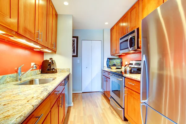 Estrecho interior de la cocina con salpicadura trasera naranja y tapas de granito — Foto de Stock