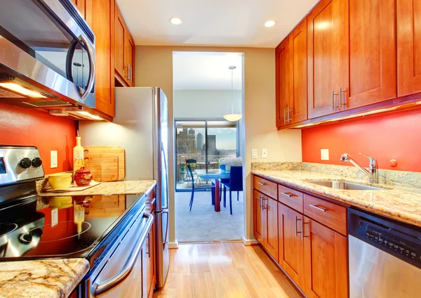 Estrecho interior de la cocina con salpicadura trasera naranja y tapas de granito —  Fotos de Stock