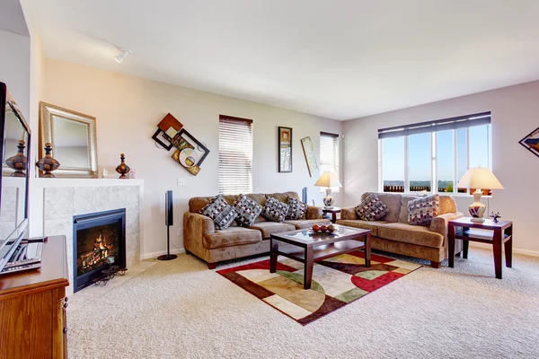 Sala de estar branca com lareira e tapete colorido — Fotografia de Stock