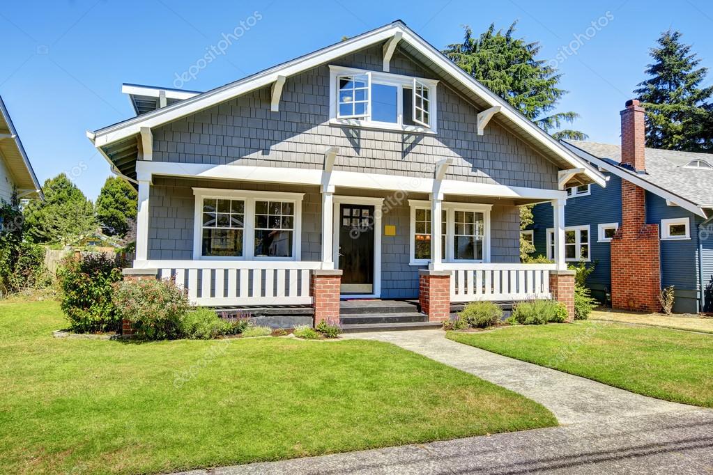 Clapboard siding house exterior. Large entance porch with brick trim and white railings