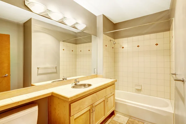 Salle de bain vide avec garniture murale en tuile et armoire ton clair — Photo