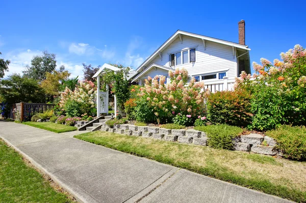 House with entance wooden archway and flower bed — Stock Photo, Image