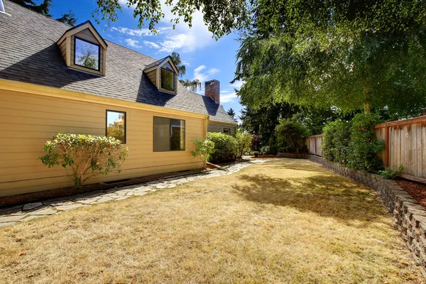 Clean backyard area with dry grass and concrete tile walkway — Stock Photo, Image