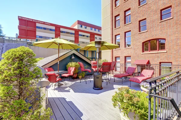 Terrazzo in legno con sedie rosse e barbecue. Edificio residenziale i — Foto Stock