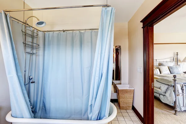 Baño con bañera y cortina azul a su alrededor — Foto de Stock