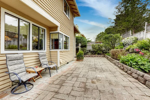 Zona de patio trasero con piso de baldosas de piedra y hermoso lecho de flores — Foto de Stock