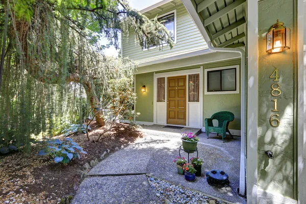 Grönt hus exteriör. ingång veranda med blomkrukor och korgvide — Stockfoto