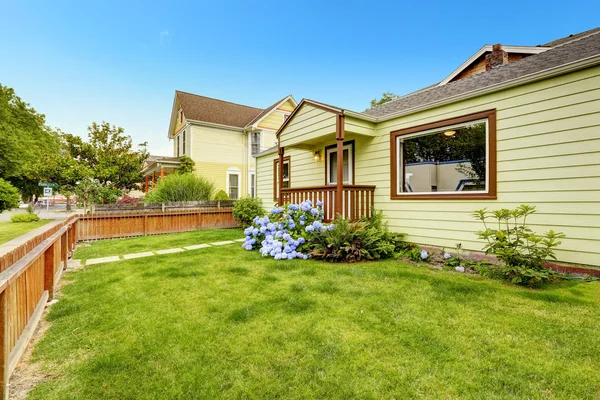 Hausexterio mit braunen Zierleisten. Vorgarten mit Rasen und Blüten — Stockfoto