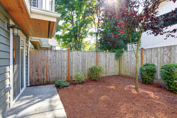 Small fenced backyard with sawdust