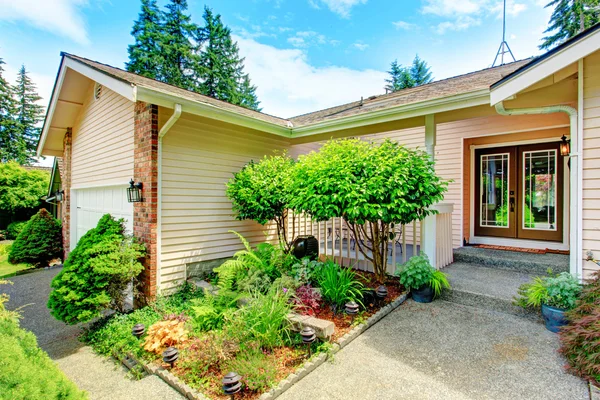 Casa exterior con porche de entrada y cama de flores . — Foto de Stock