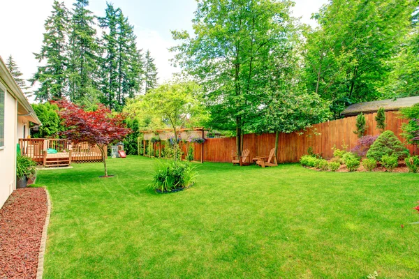 Огороженный двор с зеленой лужайкой и зоной отдыха — стоковое фото