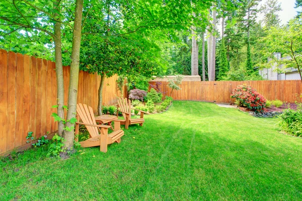 Cour arrière clôturée avec pelouse verte et coin salon — Photo