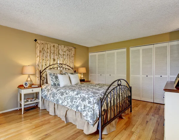 Timeless bedroom with floral bedding and hardwood floor. — Stock Photo, Image