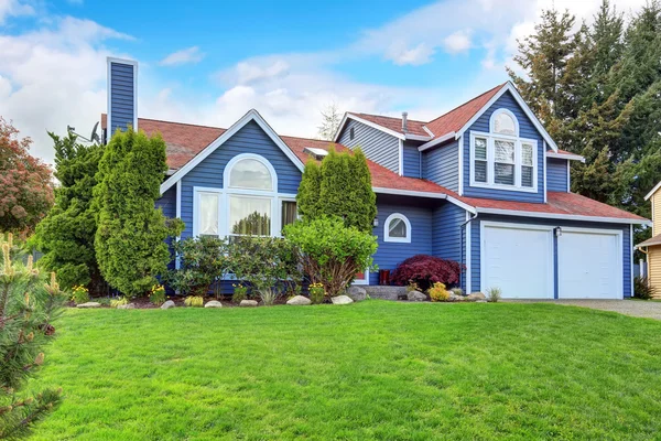 Gran casa azul con adorno blanco y un bonito césped . — Foto de Stock