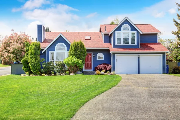 Grande casa azul com guarnição branca e um gramado agradável . — Fotografia de Stock
