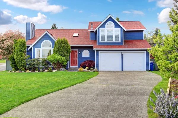 Gran casa azul con adorno blanco y un bonito césped . — Foto de Stock