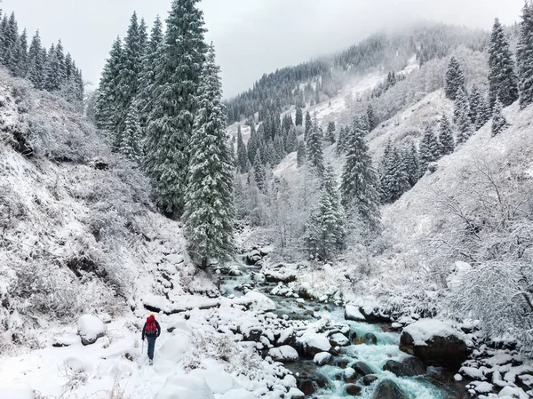 Active tourist walks in the winter in the mountains. Snow-capped mountain winter gorge with river
