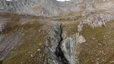 Dağ gölünden akan bir dere kayaların arasından geçer. Kensu nehri geçidinde Moraine Gölü. Kazakistan. Aero video çekimi