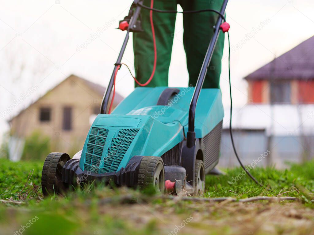 Mowing the lawn by lawnmower in the backyard. Garden background. Summer and spring season gardening background