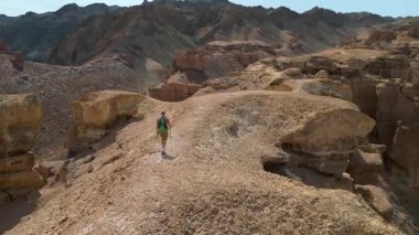 Bir turist kumlu kanyonda yürür. Sırt çantası ve yürüyüş direkleri olan bir gezgin yalnız yürür. Charyn Kanyonu