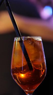 Spotlight 'taki bir kokteylin dikey video görüntüleri. Bulanık Balo Salonu Dans Salonu 'na karşı Citrus ve Ice' lı Kristal Cam. Çiftler arka planda dans ediyorlar. Yavaş çekim 2x