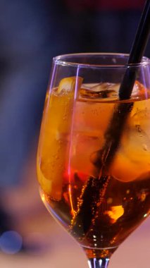 Bulanık Dans Salonu 'na karşı Citrus ve Ice' la kristal bardakta kokteyl içerken çekilmiş dikey video görüntüleri. Çiftler arka planda dans ediyorlar. Yavaş çekim 2x