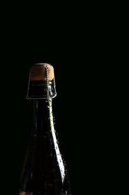 Koyu yeşil arka planda mantarlı şampanya şişesi.