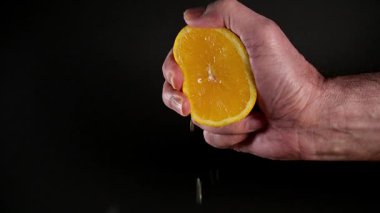 Erkek eli yarım portakalı siyaha bastırıyor.