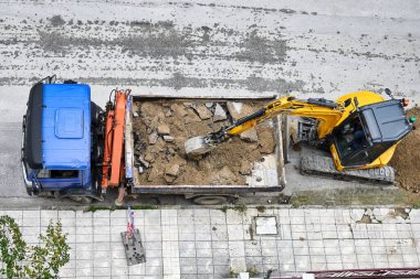 excavator loading debris on dump truck