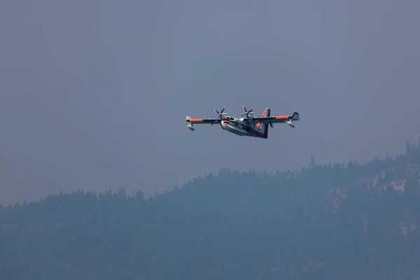 2014年9月7日 オレゴン州プロスペクト近くのロストクリーク湖で煙で満たされた空の山の上に水をすくう準備をする小さな消防飛行機 — ストック写真