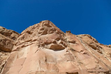 Bronzlaşmış kumtaşı kayalıkları mavi gökyüzüne yükseliyor. New Mexico 'daki Chaco Kanyonu' nun tarihi yerinde parlak güneş ışığıyla aydınlanıyor..