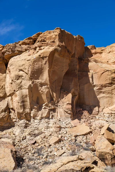 チャコ キャニオンの下の土石流のフィールドに大きな岩と古代の割れた砂岩の崖は 明るい青空 — ストック写真