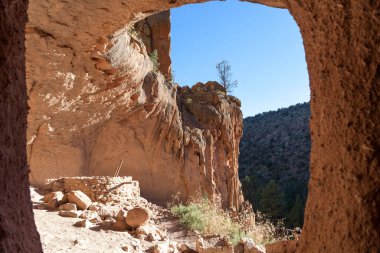 New Mexico 'daki Bandelier Ulusal Anıtı' ndaki tuğla ve kiva yapılarını gösteren kumtaşı bir uçurumun tepesindeki Pueblo mağarasında yaşayan insanlar..