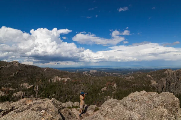南达科他州卡斯特州立公园 一位摄影师站在花岗岩岩层上 拍摄具有动态背景的照片 — 图库照片