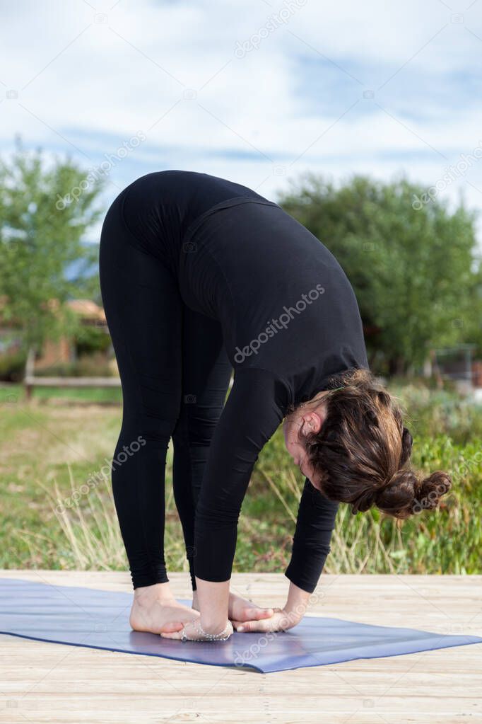 A woman participating in an afternoon outdoor yoga class on a wooden platform at a farm.