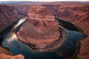 Horseshoe Virajı 'ndaki yüksek kayalıklardan aşağıya bakınca tekneleri ve Colorado Nehri kıyısındaki insanları gece için kamp kurarken görüyorum..