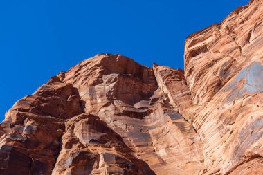 Glen Kanyonu 'nun yüksek kırmızı kumtaşı duvarları parlak güneş ışığıyla aydınlatılan ve parlak mavi gökyüzü ile kaplı yaşlı kayaların arasında birkaç çatlak var..