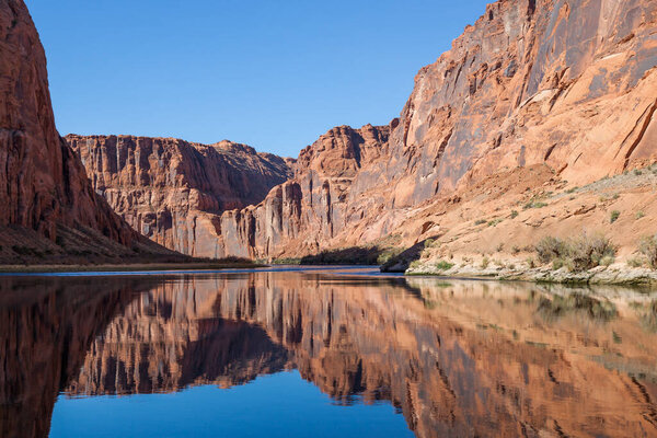 Light, shadow, and calm water make a perfect combination to reflect the sandstone walls of Glen Canyon onto the Colorado River in an artistic view.