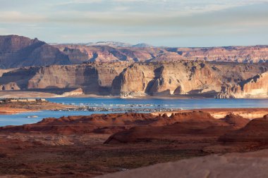 Kızıl kumtaşı, Powell Gölü 'ndeki işlek Wehweap limanına, oradan da sabah güneşiyle aydınlanan soluk kumtaşı uçurumlarına ve uzaktaki karanlık ve büyük dağlara götürür..