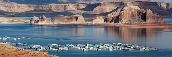 Large yachts and party boats fill the Wahweap Marina on the beautiful and scenic Lake Powell with eroded sandstone features in the distance near Page, Arizona.