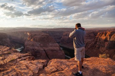 Horseshoe Bend, Arizona / ABD - 25 Ekim 2014: Bir adam gün batımında Arizona 'da Horseshoe Bend yakınlarında bir uçurumun kenarında durur..