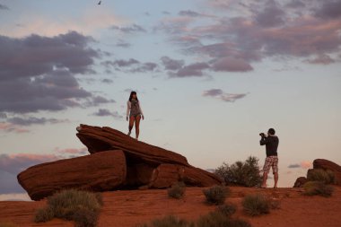 Horseshoe Bend, Arizona / USA - 25 Ekim 2014: Bir erkek Arizona, Page yakınlarındaki Horseshoe Bend 'de öğleden sonra ışığı solan turuncu kumtaşı kaya oluşumunda duran bir kadının fotoğrafını çeker..