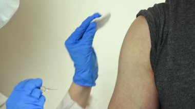 Mavi eldivenli hemşire grip aşısı yapıyor.